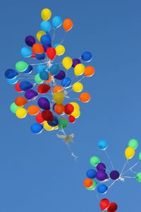 Low angle view of multi colored balloons against clear sky