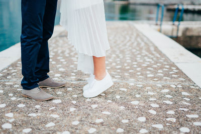 Low section of couple standing on footpath