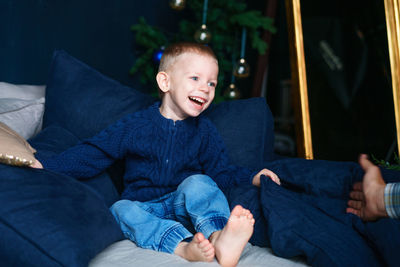 Cute little blond toddler boy in blue sweater is having fun and playing