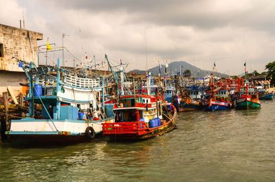 Boats moored at harbor against sky