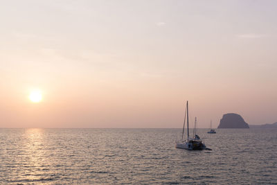 Boat sailing in sea against sky during sunset