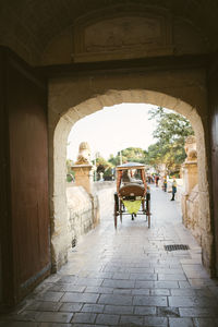 Rear view of people walking on footpath amidst buildings