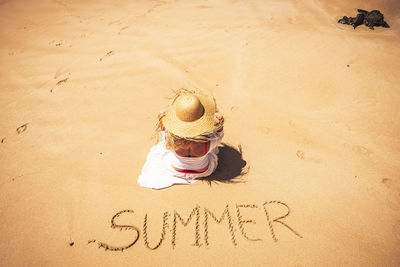 High angle view of person wearing hat on sand at beach