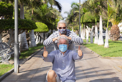 Portrait of senior couple wearing mask sitting at park