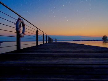 Pier over sea against sky during sunset