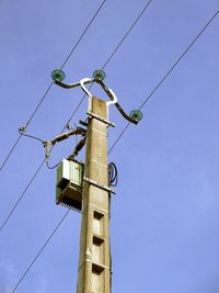 Low angle view of power lines against blue sky