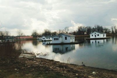 Houses by lake against sky