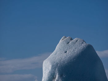 Low angle view of snow covered mountain against blue sky