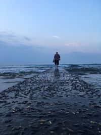 Rear view of man in sea against sky