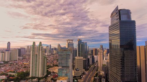 Aerial view of buildings in city against cloudy sky