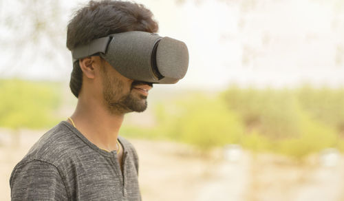 Side view of smiling man wearing virtual reality simulator at home