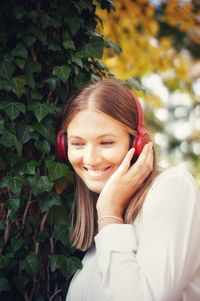 Portrait of smiling young woman using phone outdoors