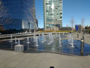 Reflection of bare trees in swimming pool against sky