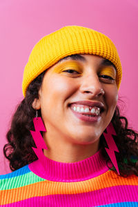 Close-up portrait of young woman against yellow background