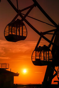 Low angle view of silhouette cranes against sky during sunset