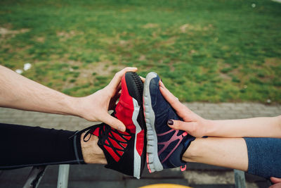 Low section of friends stretching legs while exercising in public park