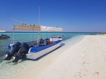 Sailboats moored on beach against clear blue sky