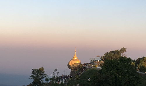 View of trees and building against sky during sunset