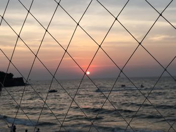 Scenic view of sea seen through chainlink fence