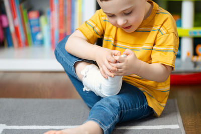 A little toddler boy holds his leg in a cast with his hands. fracture of a foot and finger 