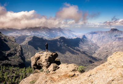 Man standing on rock against sky