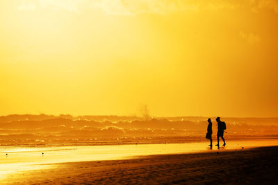 Silhouette of people on beach at sunset