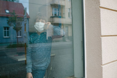 Man standing by glass window of building