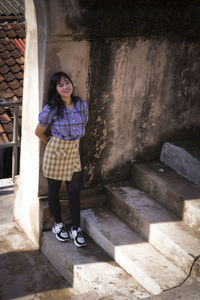 Portrait of woman standing against wall