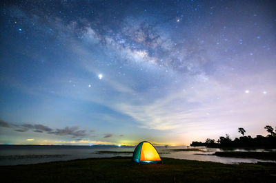 Tent on beach against sky at night