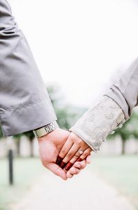 Cropped image of groom holding hands of bride