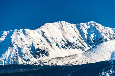 Scenic view of snowcapped mountains against clear blue sky