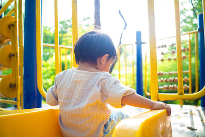 Rear view of boy sitting at playground