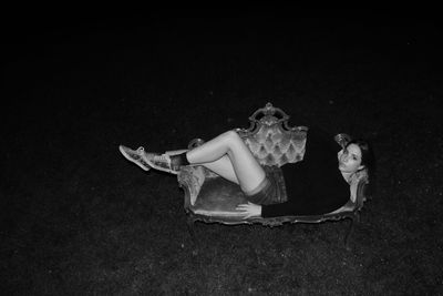 Portrait of woman lying on sofa in park at night
