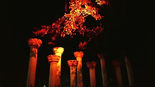 Low angle view of lit candles on wall at night