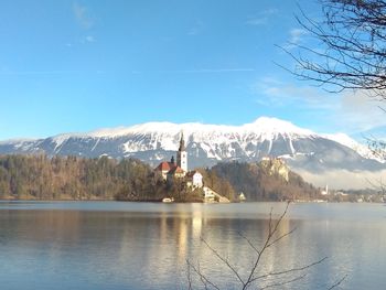 Scenic view of lake and snowcapped mountains against blue sky