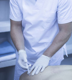 Midsection of doctor injecting patient