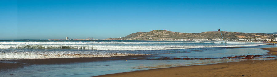 Scenic view of beach against clear blue sky