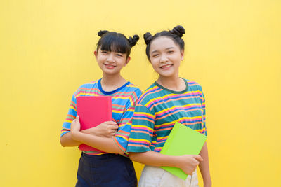 Portrait of a smiling young woman against yellow background