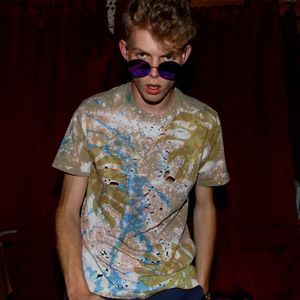 Portrait of young man wearing sunglasses by curtain