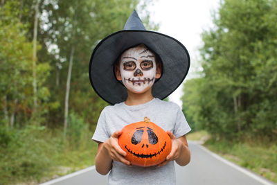 Portrait of boy holding pumpkin outdoors
