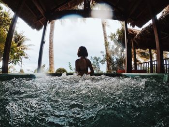 Rear view of girl on shore against sky