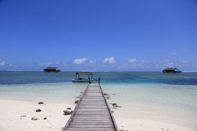 Pier over sea against clear blue sky