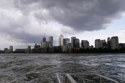 Sea by modern buildings against sky in city