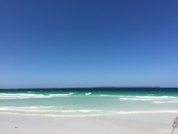 Scenic view of beach against clear blue sky