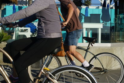 Low section of people riding bicycle on road in city