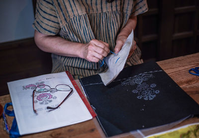 Midsection of man holding paper on table