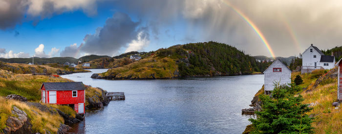 Panoramic view of rainbow over buildings and trees against sky