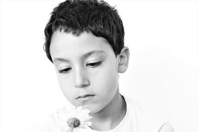 Close-up of boy holding flower against white background