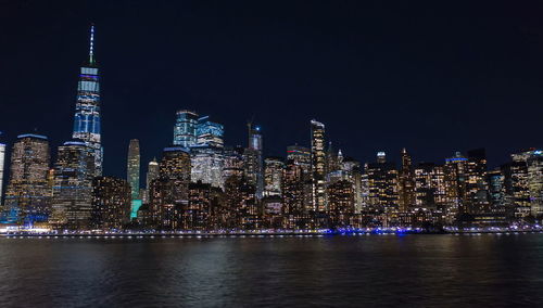 Illuminated modern buildings in city against sky at night