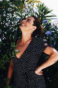 Portrait of a smiling young woman standing against plants
